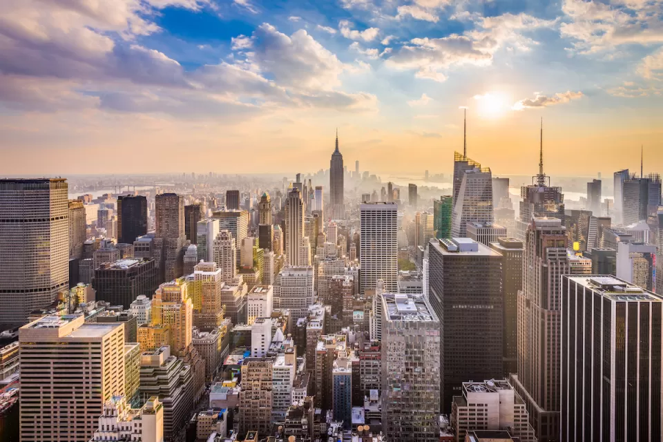 New York City skyline with Empire State Building in center and blue cloudy sky.